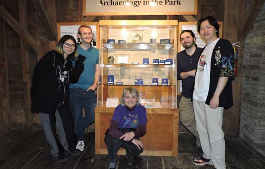 Sherene Baugher and four museum class students by the final permanent archaeology exhibit in the mill museum at Robert Treman State Park